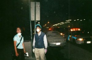 Heidi Singer at Ground Zero with mask under her chin and dust covering car behind her