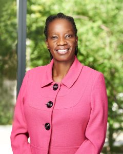 Professional headshot of Prossy Kiddu Namyalo wearing a pink suit jacket