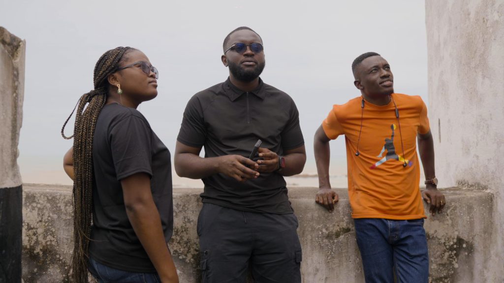 DLSPH students stand against a concrete balcony wall in thought. This is a still from a documentary on the risks of heavy mental contamination in Ghana.