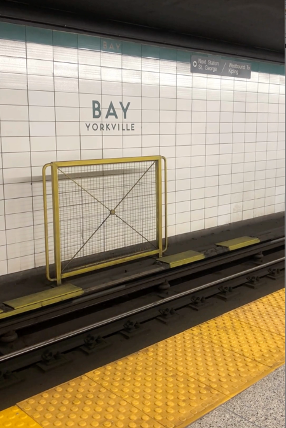 View of subway tracks and a sign on the wall that says "Bay Yorkville".